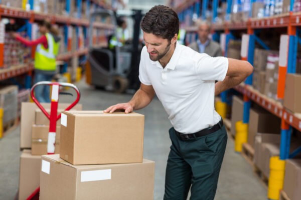 Focus of worker having a backache in a warehouse